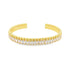 A gold cuff bracelet sparkles with a continuous row of oval-cut white cubic zirconia stones beneath a beaded edge.