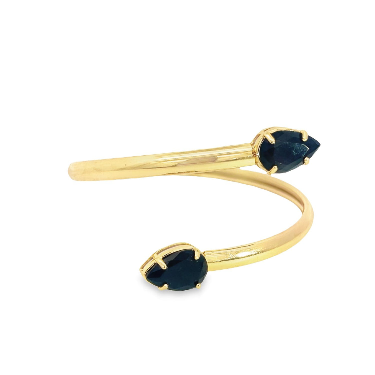 A bypass gold ring features two opposing pear-cut dark sapphires in prong settings against a plain white background.