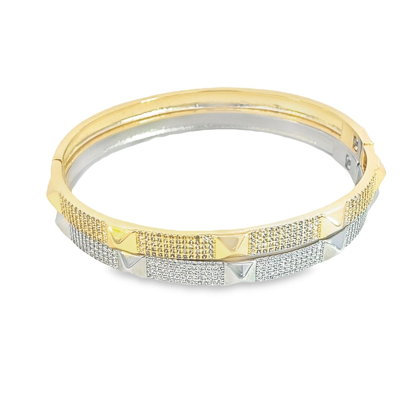 A two-tone gold and silver hinged bangle bracelet sparkles with pavé-set cubic zirconia and pyramid studs.