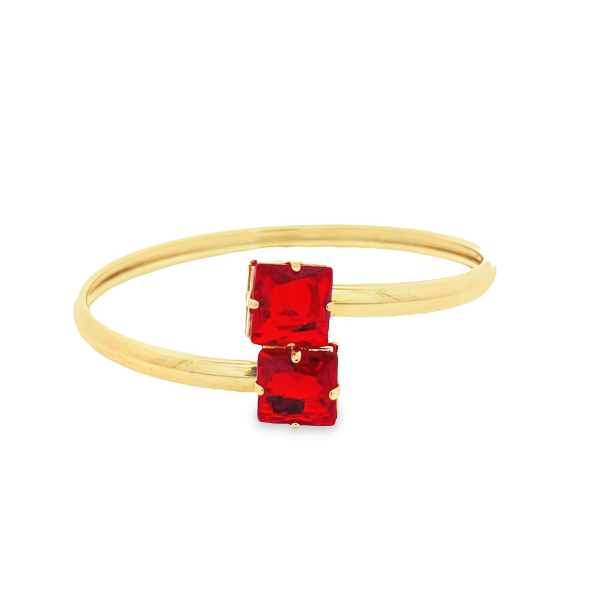A sleek gold bangle bracelet features two vibrant square-cut red stones set end-to-end at the center.