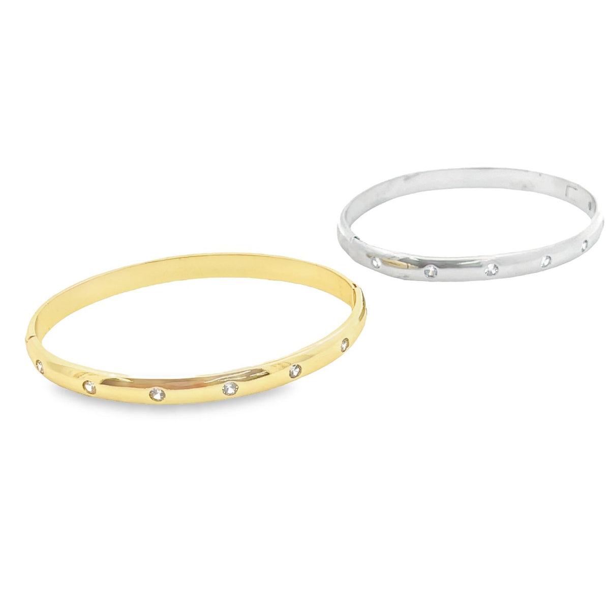 Two elegant diamond bangle bracelets rest side by side, featuring one gold and one silver polished band bezel-set with sparkling gemstones.