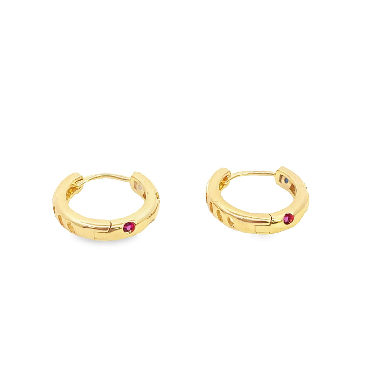 A pair of gold huggie hoop earrings features small embedded red gemstones and decorative cutouts along the bands against a white background.