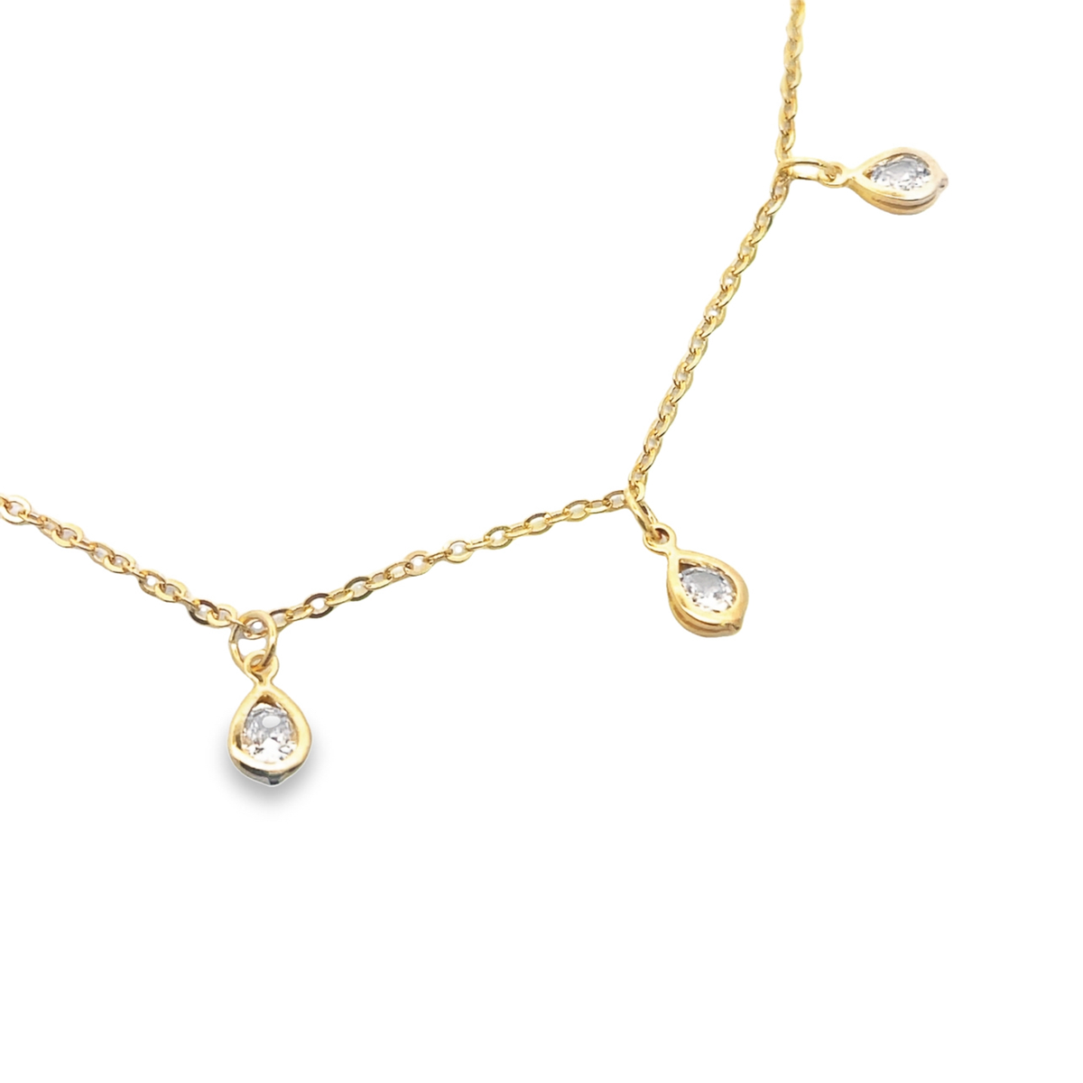 A delicate gold chain necklace features three sparkling teardrop-shaped diamond pendants dangling gracefully against a white background.