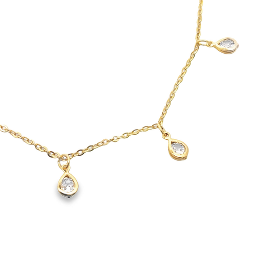 A delicate gold chain necklace dangles three sparkling teardrop-shaped diamond pendants against a white background.