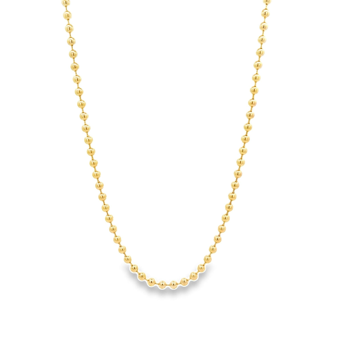 A delicate gold ball chain necklace drapes against a clean white background.