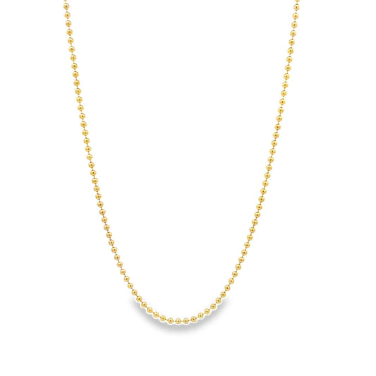 A delicate gold ball chain necklace hangs against a white background.