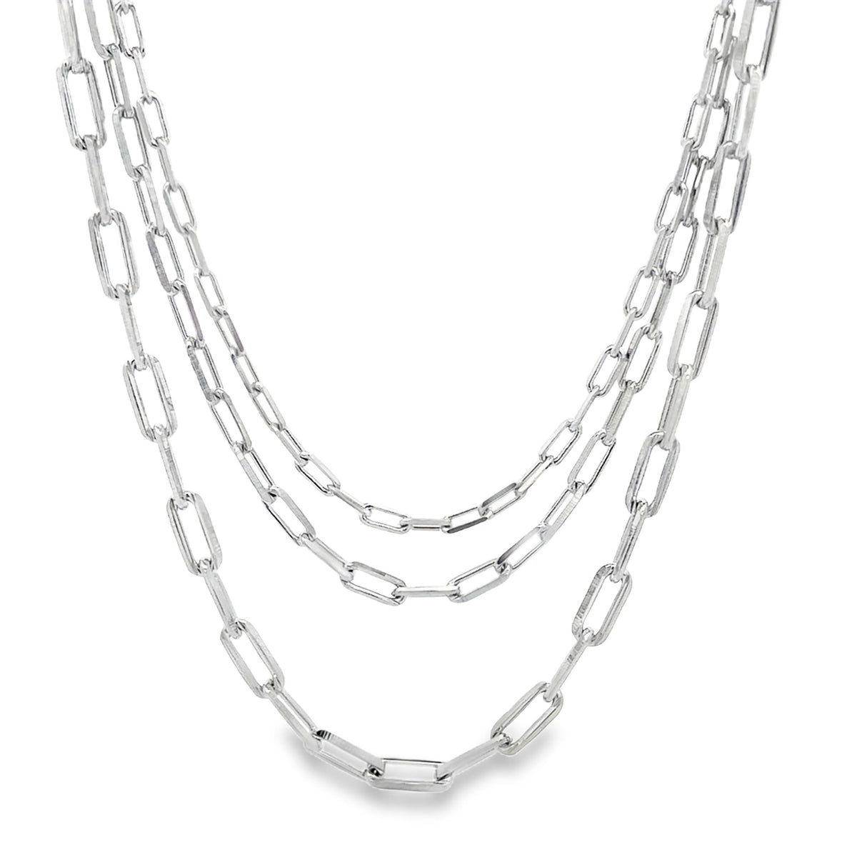 A layered silver paperclip chain necklace drapes gracefully against a white background.