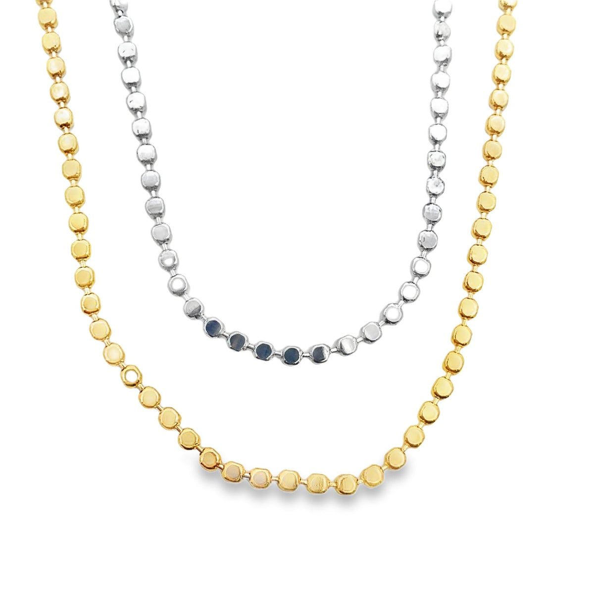 Two layered beaded necklaces, featuring one gold chain and one silver chain, display delicate metallic links against a white background.