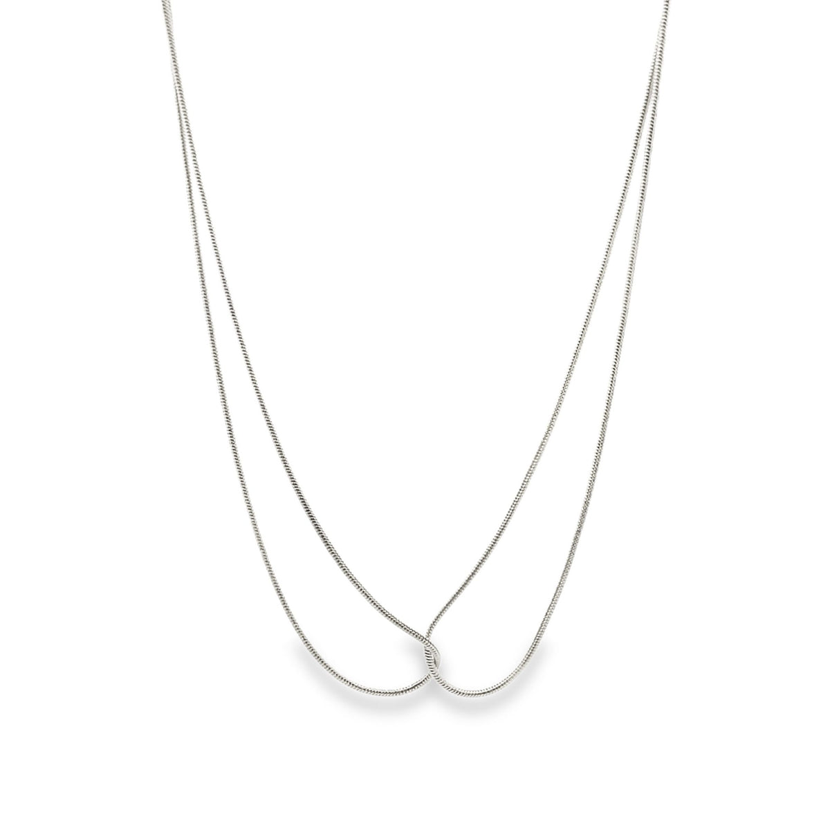 A delicate silver snake chain necklace gracefully loops and crosses over itself against a clean white background.