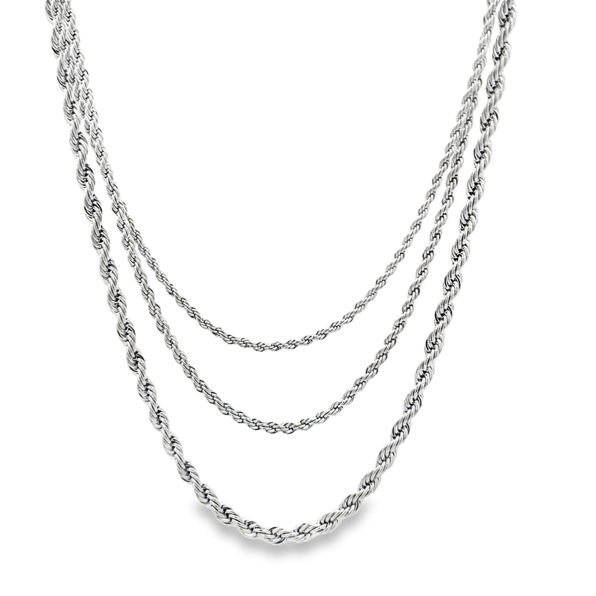 A layered silver rope chain necklace drapes gracefully against a clean white background.