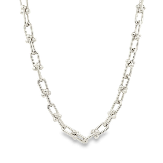 A polished silver link chain necklace rests in a gentle curve against a clean white background.
