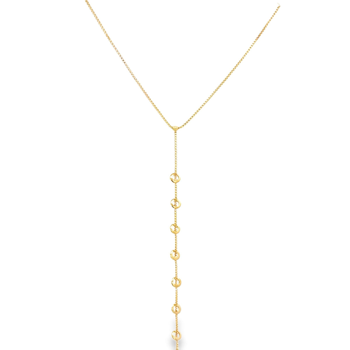 A delicate gold lariat necklace features a fine chain cascading down with evenly spaced circular charms.