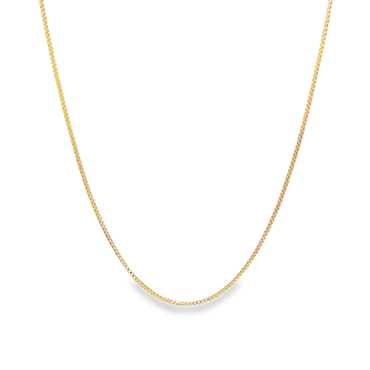 A delicate gold box chain necklace rests in a gentle curve against a plain white background.