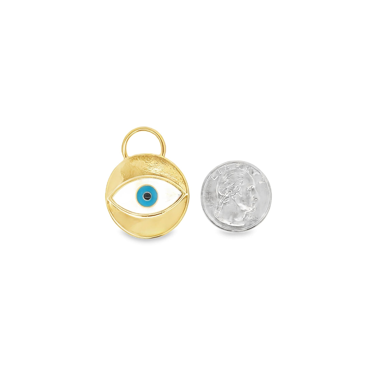 A round gold evil eye pendant rests next to a US quarter coin to display its actual size.