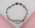 A shiny silver puffed mariner link bracelet rests neatly on a soft white and pink display surface.