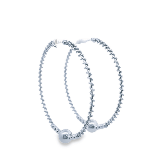A pair of textured silver hoop earrings featuring decorative ball charms rests against a clean white background.