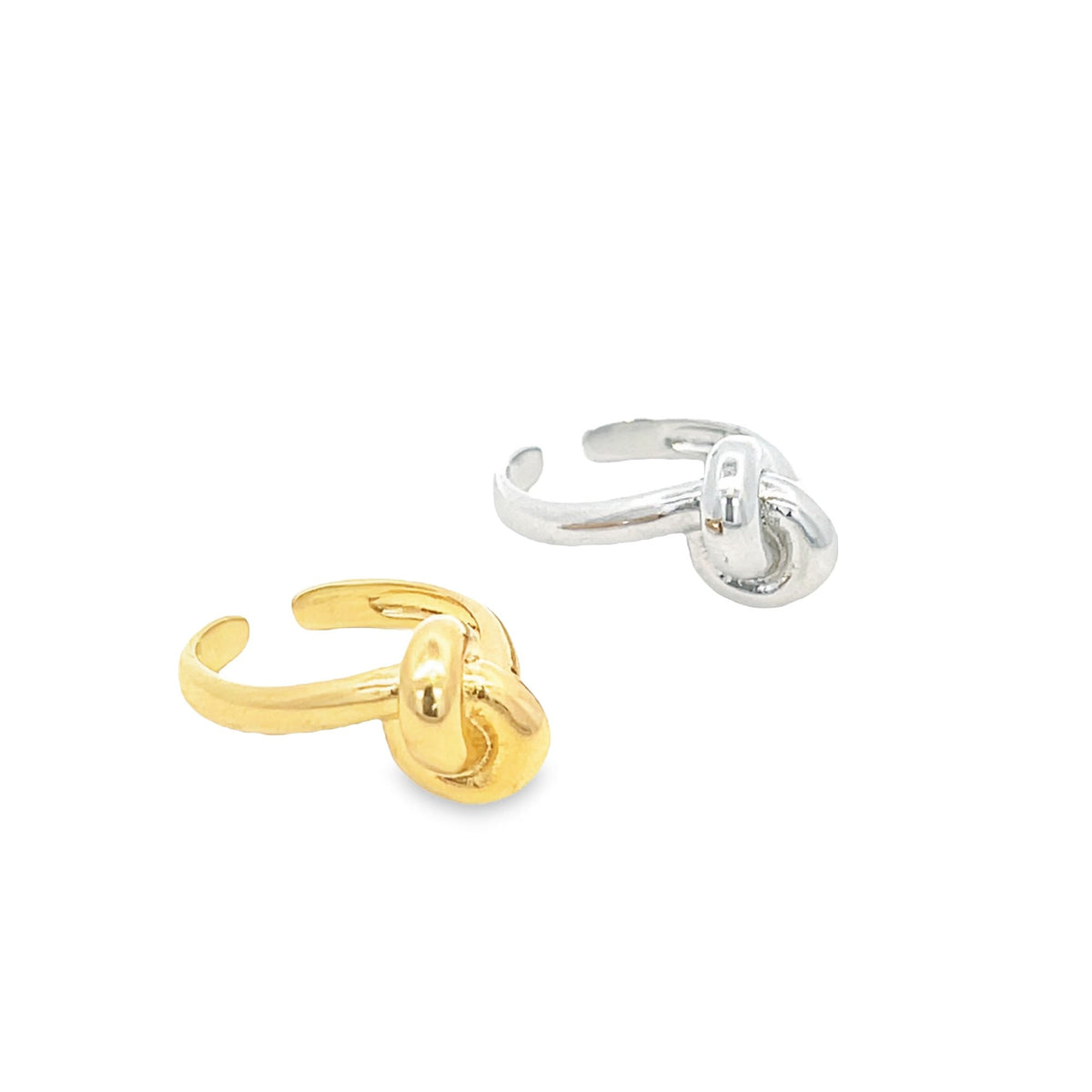 A gold and a silver knot-shaped ear cuff rest side by side on a clean white background.