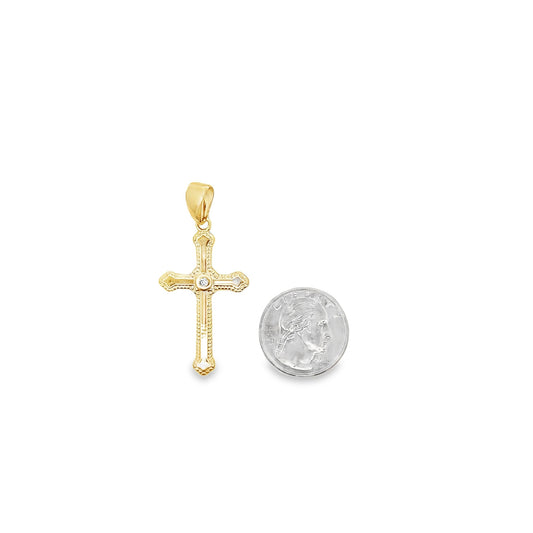 A gold cross pendant with a center diamond rests next to a quarter for size comparison.