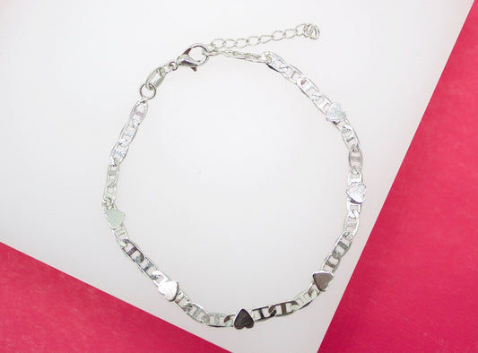 A silver link bracelet featuring alternating small hearts and "ILoveYou" lettering rests against a white and pink background.