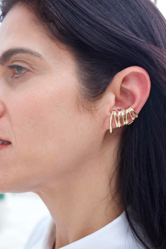 A woman wears a stylish multi-band gold ear cuff on her cartilage.