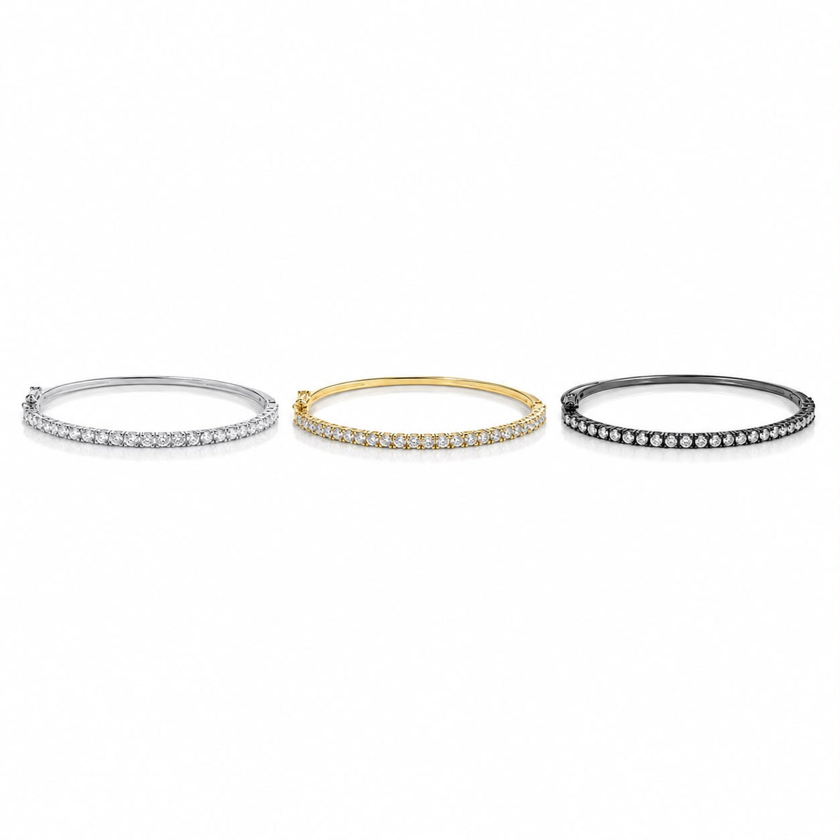 Three diamond tennis bracelets in silver, yellow gold, and black metal rest side by side against a clean white background.