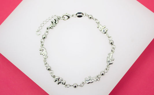 A delicate silver elephant charm bracelet rests against a pink and white display background.