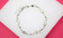 A delicate silver elephant charm bracelet rests against a pink and white display background.