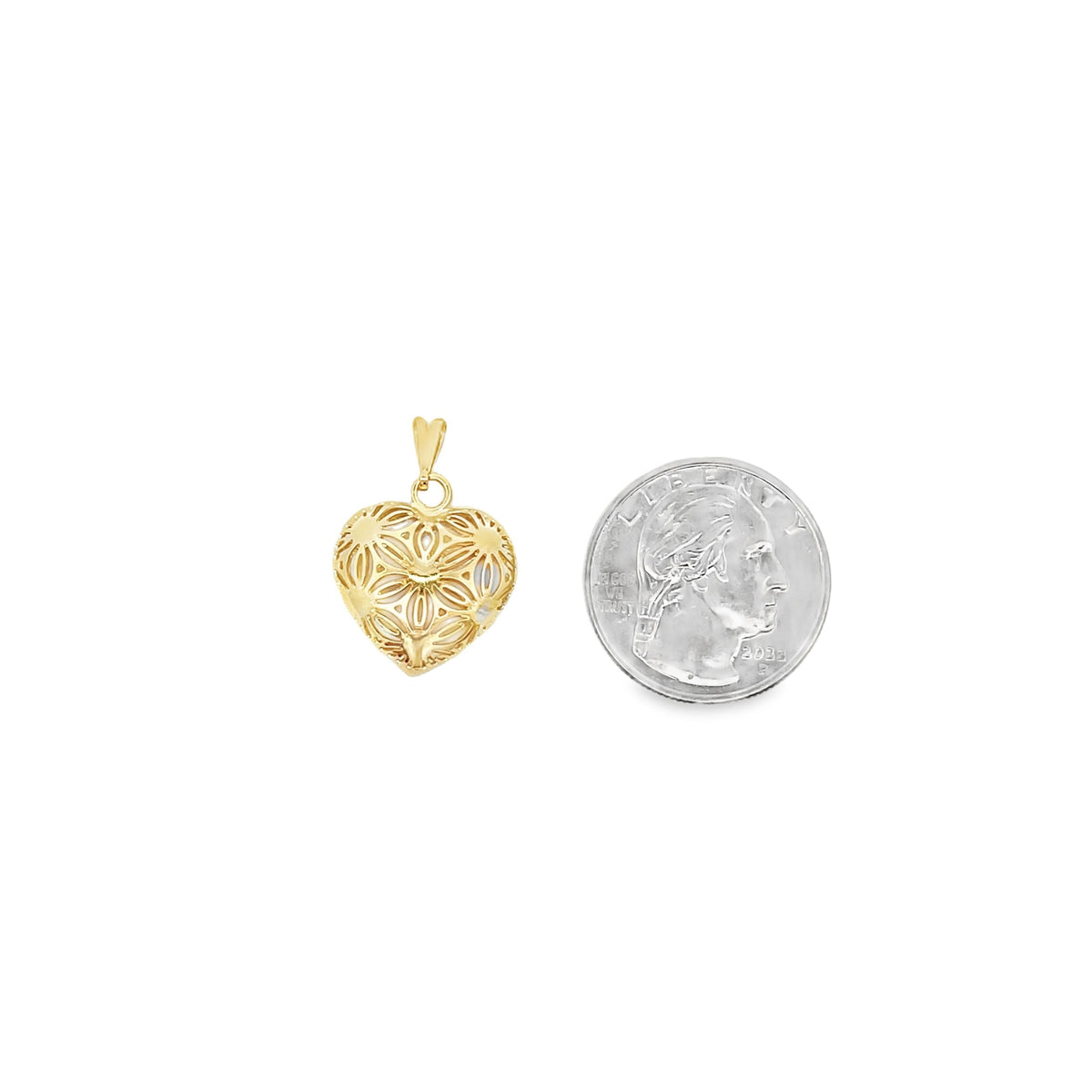 A gold filigree heart pendant sits beside a US quarter for size comparison on a white background.