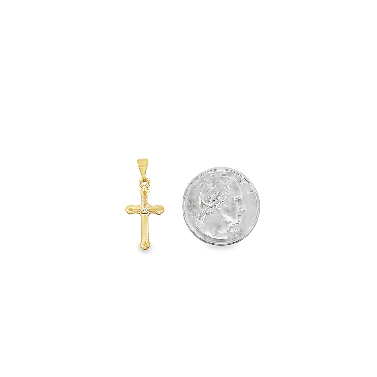 A small gold cross pendant rests beside a quarter to show its size.