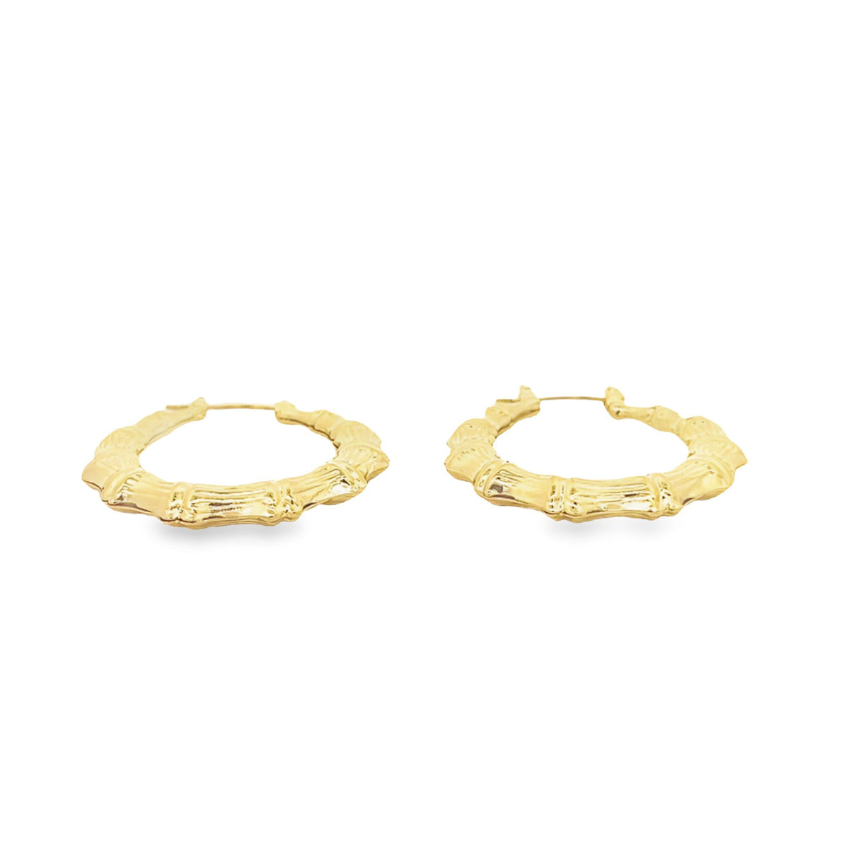 A pair of shiny gold bamboo hoop earrings rests flat against a clean white background.