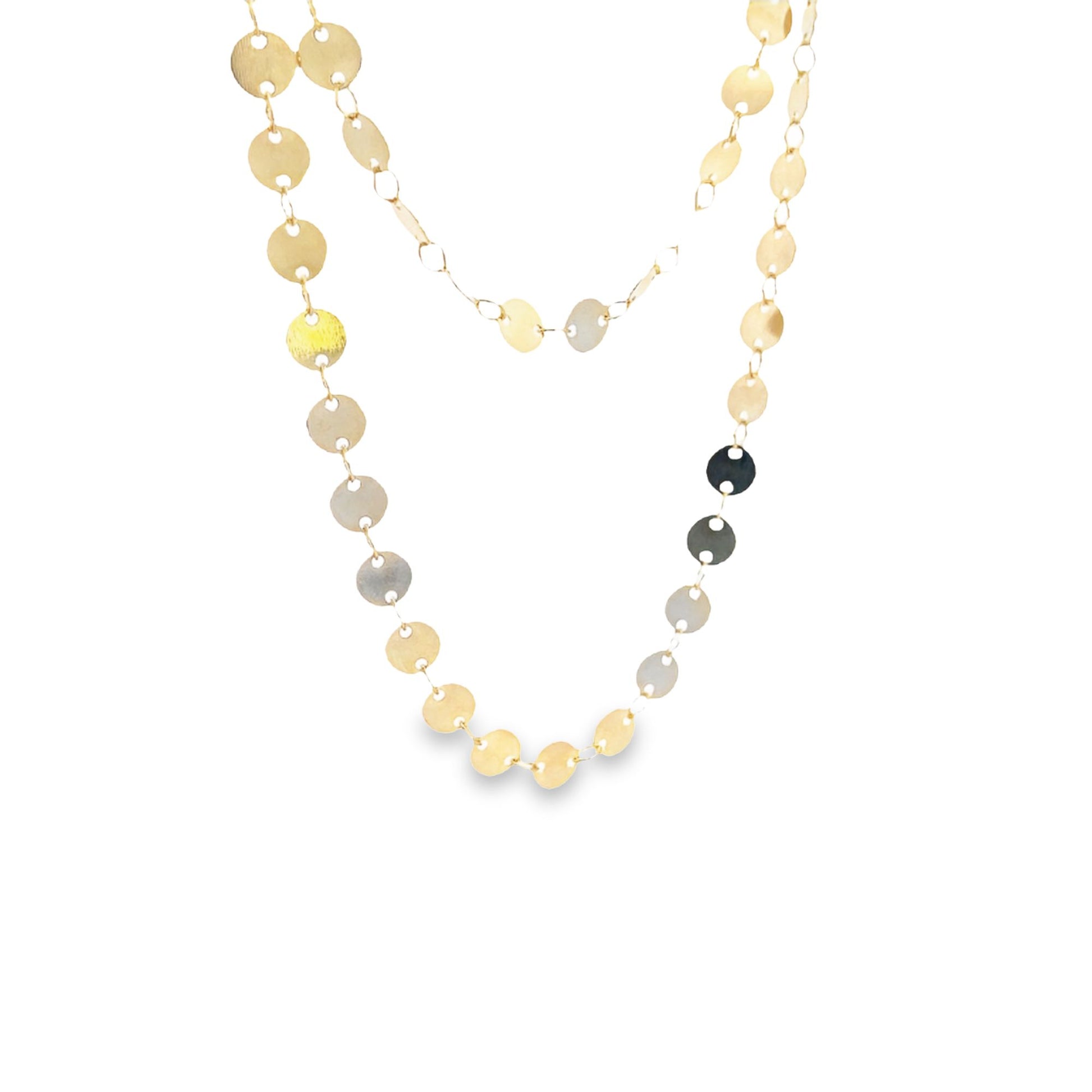 A delicate gold chain necklace drapes against a white background, featuring dangling circular metallic discs that catch the light.