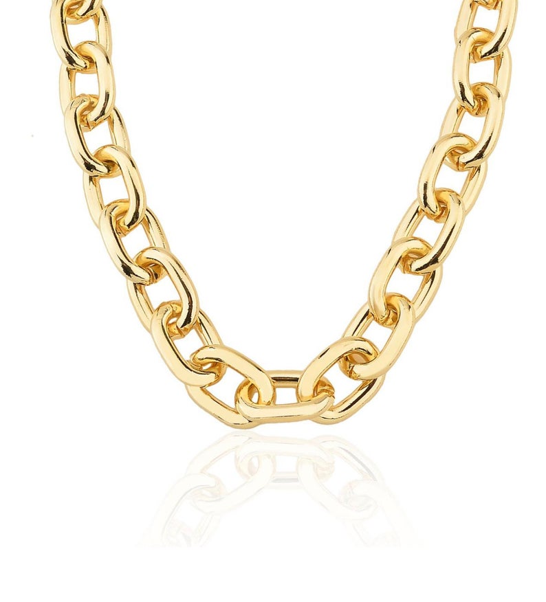 A thick gold chain-link necklace rests in a gentle curve against a white background with a soft reflection underneath.
