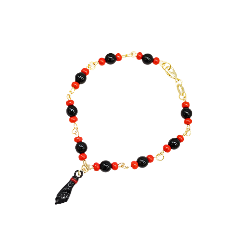 A gold chain bracelet features alternating red and black beads and hangs with a black figa charm against a white background.