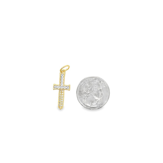 A gold cross pendant encrusted with sparkling diamonds rests next to a US quarter for size comparison.