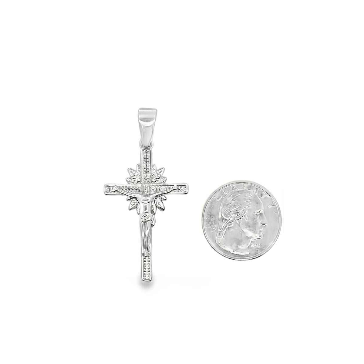 A silver crucifix pendant rests beside a US quarter for scale.