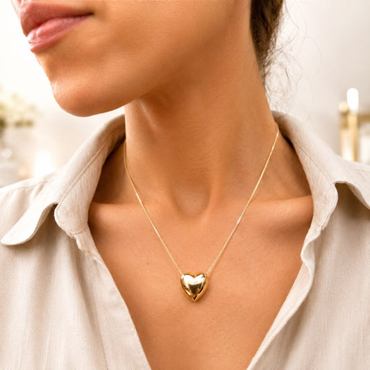 A woman wearing a gold heart pendant necklace on a delicate chain.