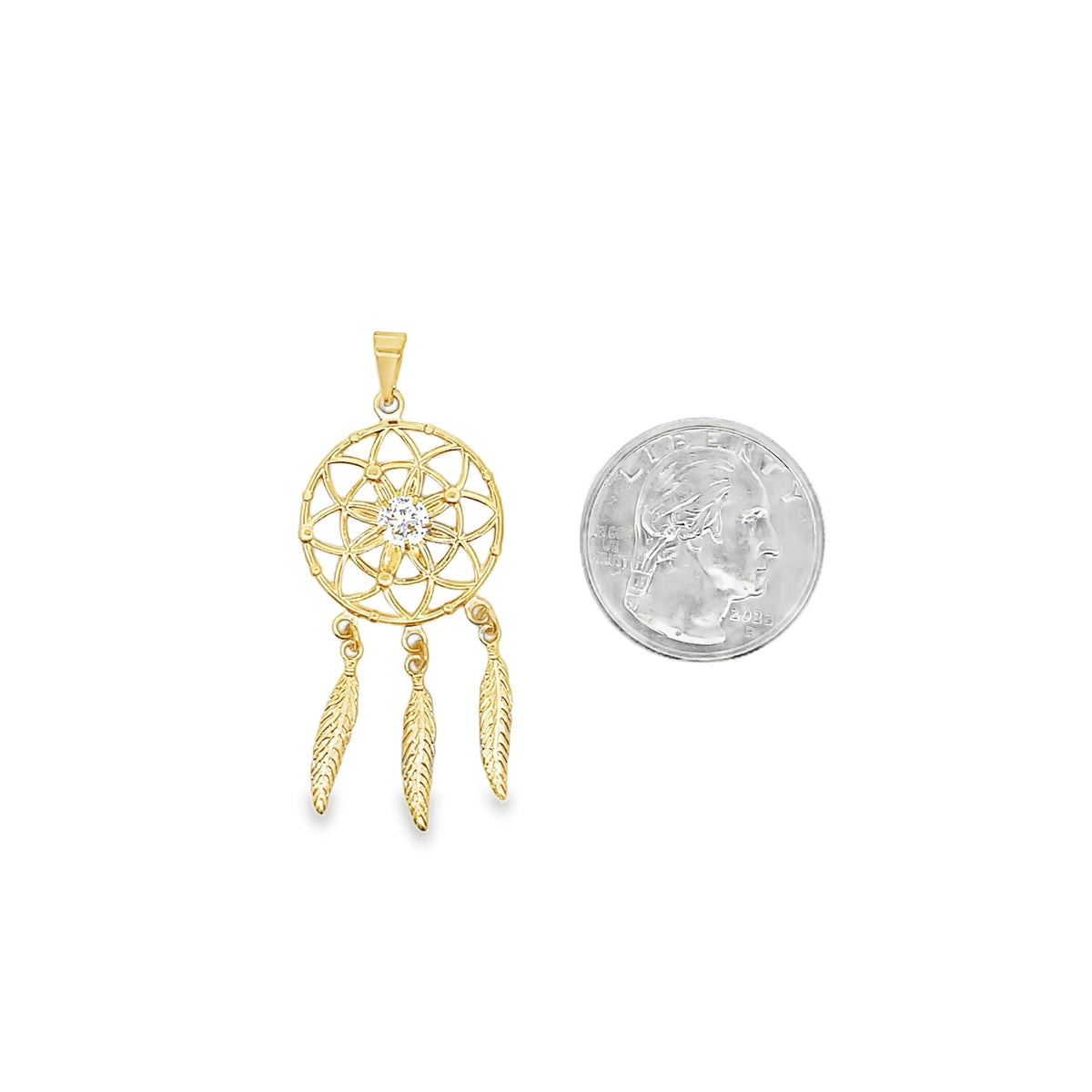 A delicate gold dreamcatcher pendant with a central cubic zirconia and hanging feathers sits next to a US quarter for scale.