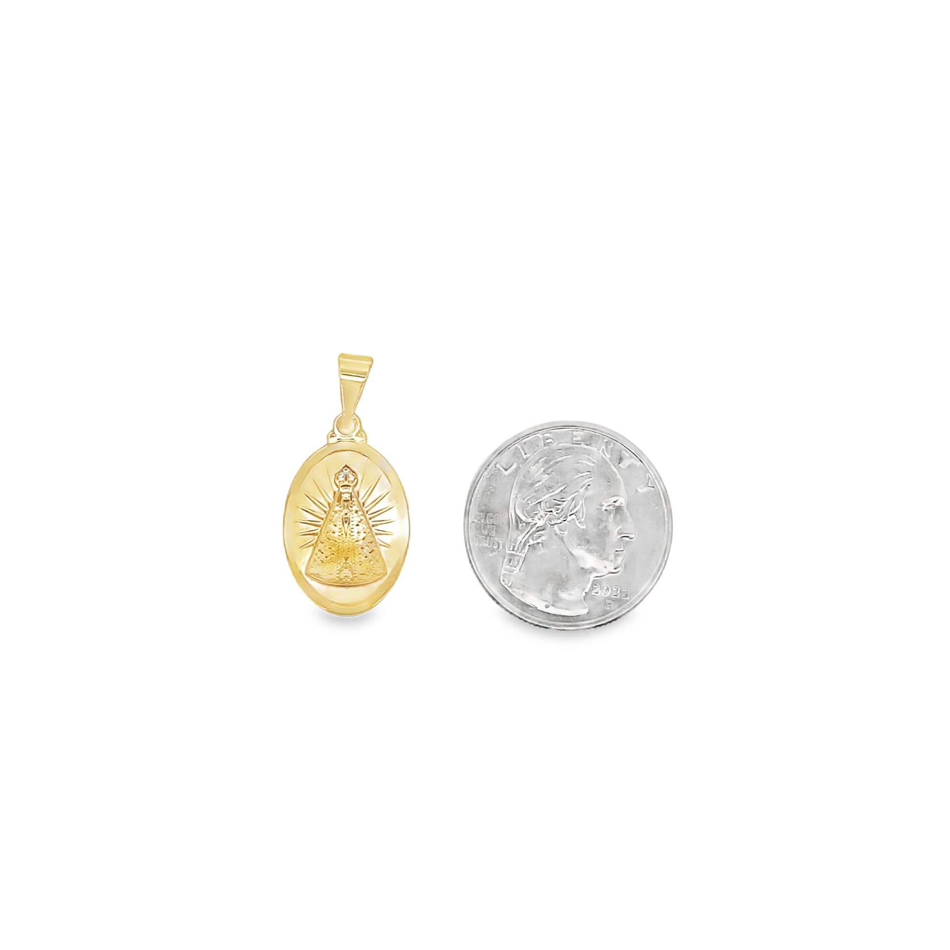 An oval gold Nossa Senhora Aparecida pendant rests next to a US quarter for size comparison.