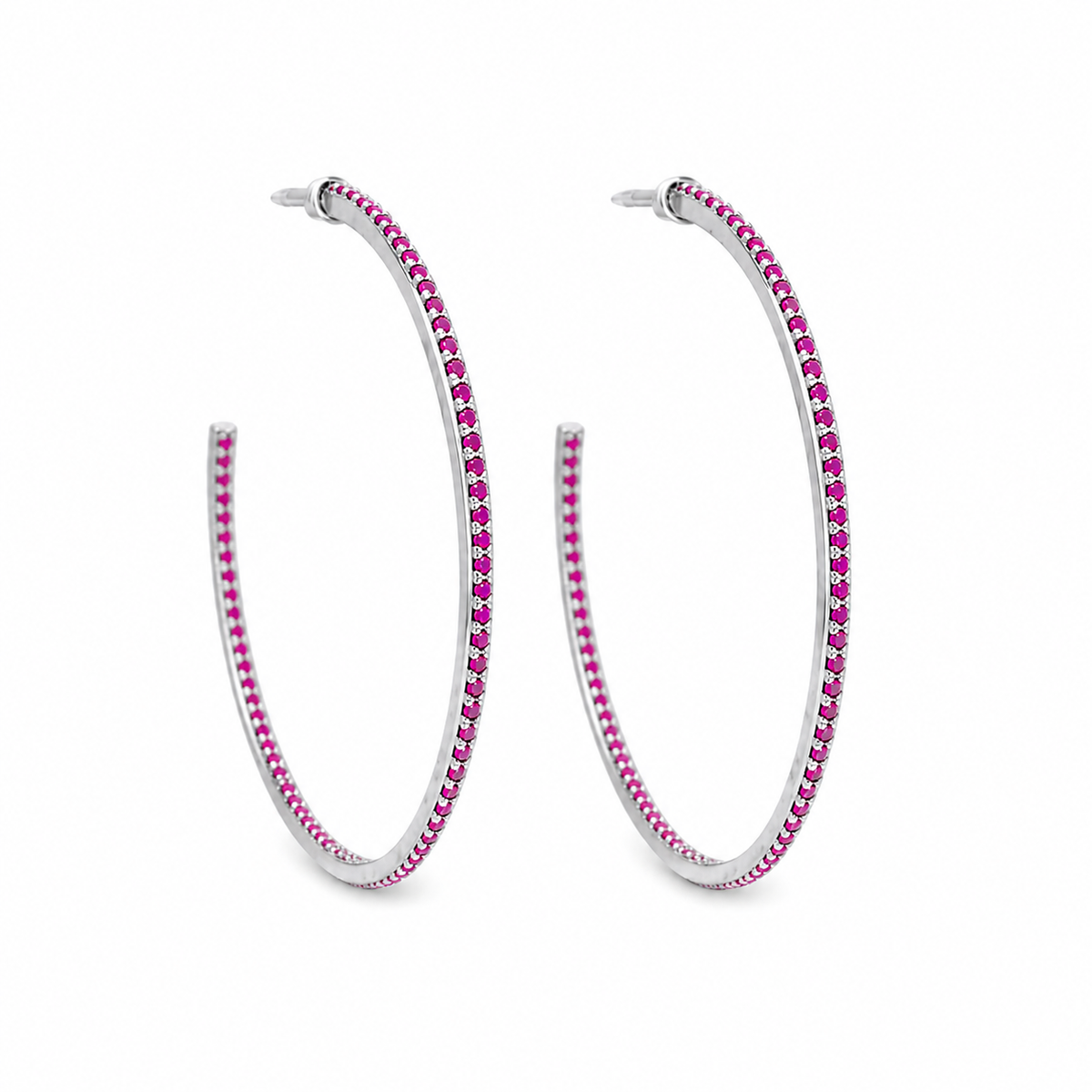 A pair of silver hoop earrings features a delicate row of vibrant pink stones against a white background.