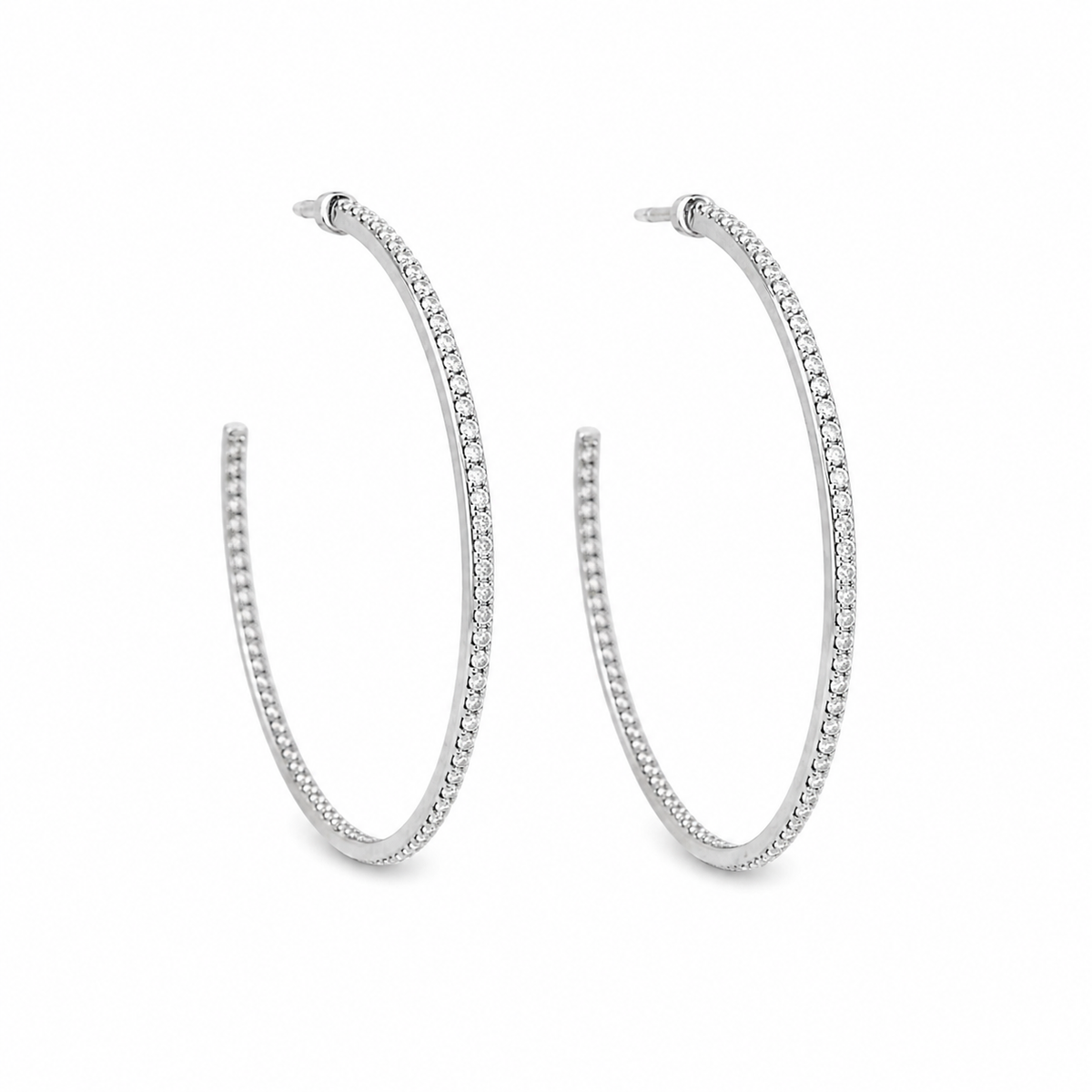 A pair of elegant silver hoop earrings encrusted with sparkling diamonds rests against a clean white background.