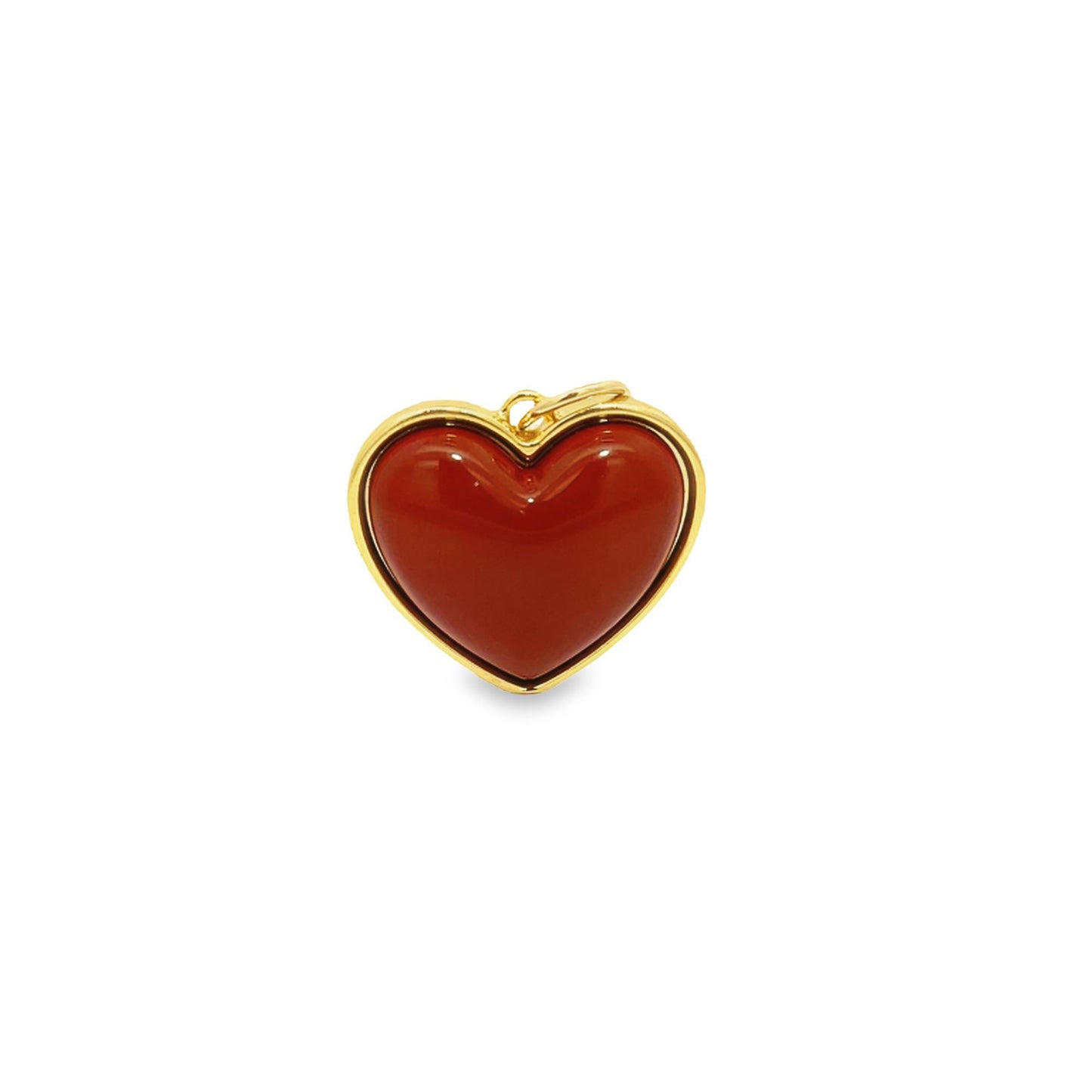A polished red carnelian heart pendant set in gold rests against a plain white background.