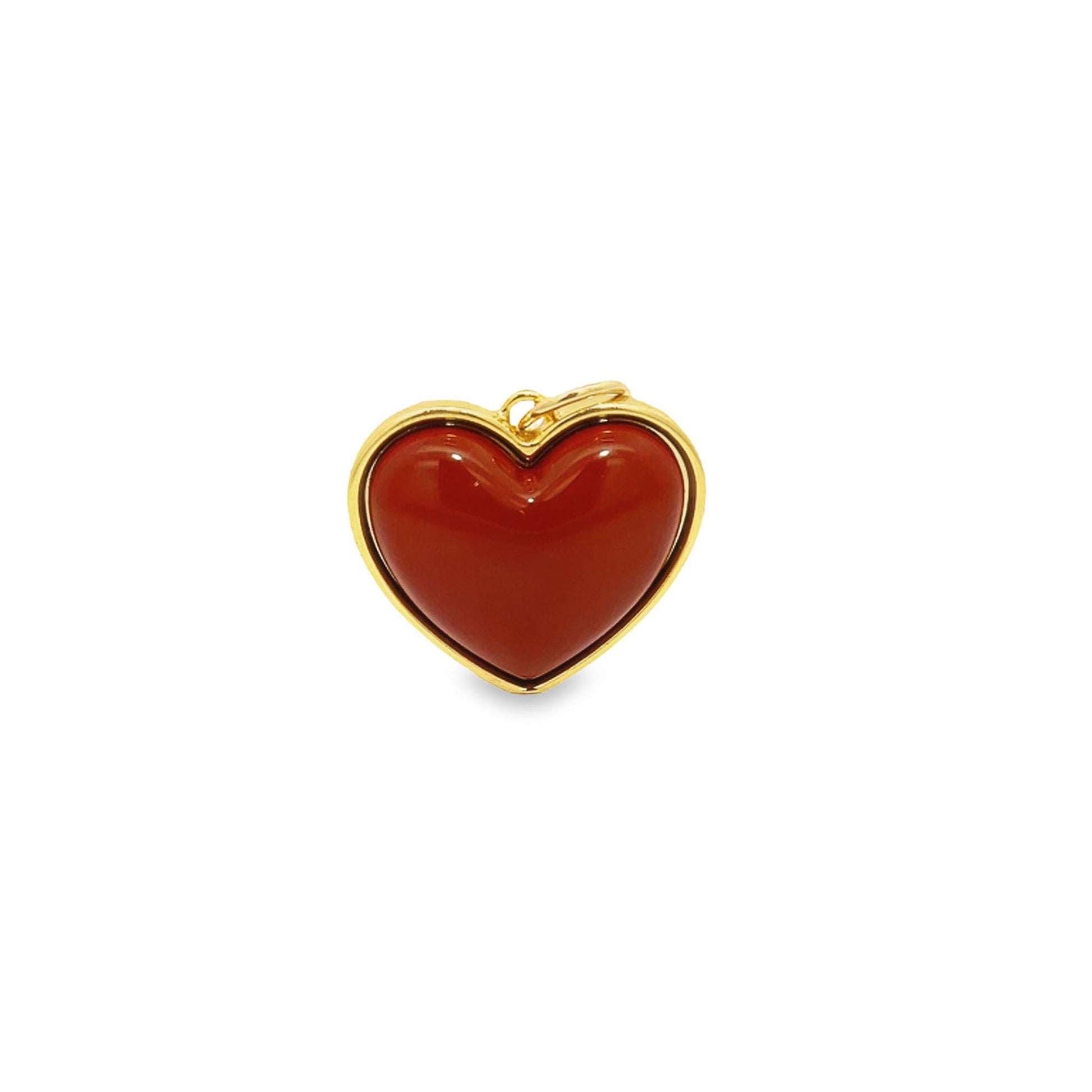 A polished red carnelian heart pendant set in gold rests against a plain white background.