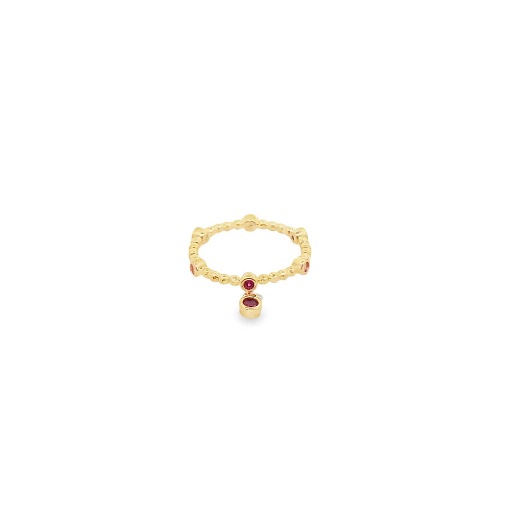 A delicate gold beaded ring features a dangling red gemstone charm against a clean white background.