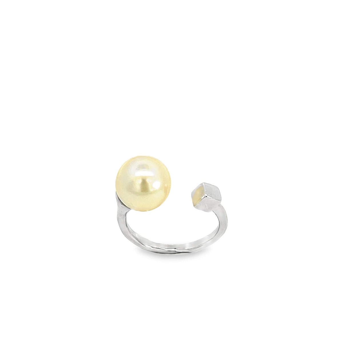 A modern white gold ring features a lustrous golden pearl on one end and a small geometric cube on the other.