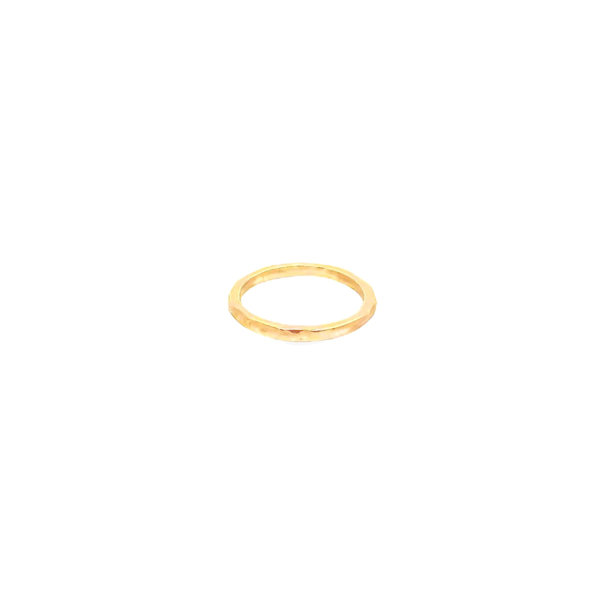 A minimalist gold stacking ring features a delicate, hammered texture against a clean white background.