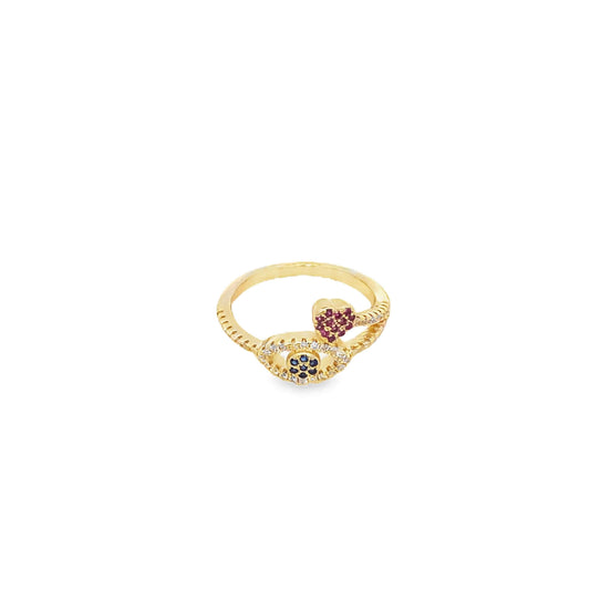 A gold ring features a sparkling evil eye motif accented with blue and white stones, alongside a small pink gemstone heart.
