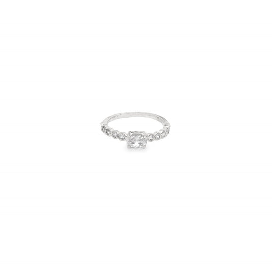 A delicate silver ring features a central cushion-cut gemstone accented by sparkling pavé diamonds along the band against a clean white background.