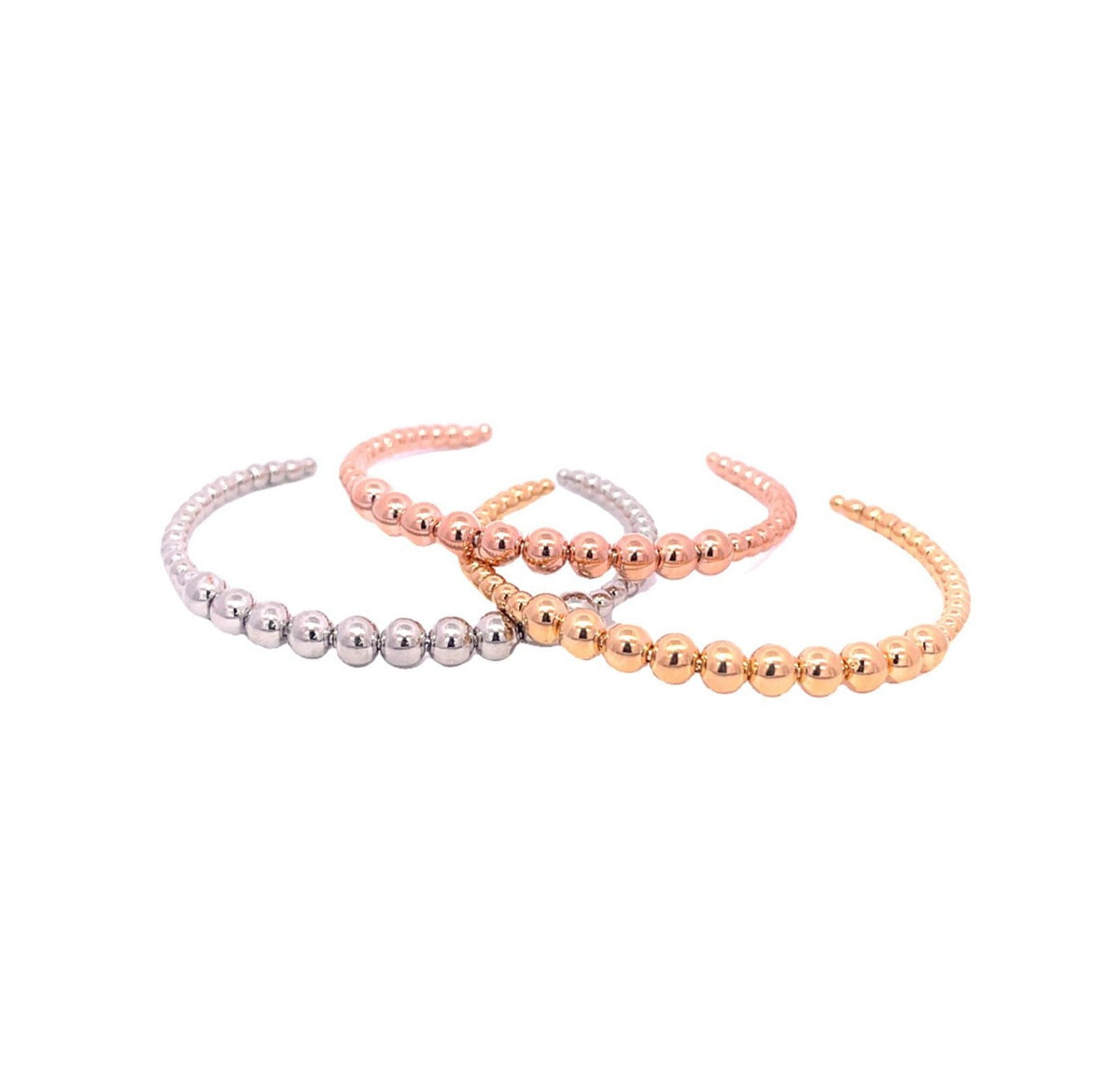 Three delicate beaded cuff bracelets in silver, rose gold, and yellow gold display their polished spheres against a plain white background.