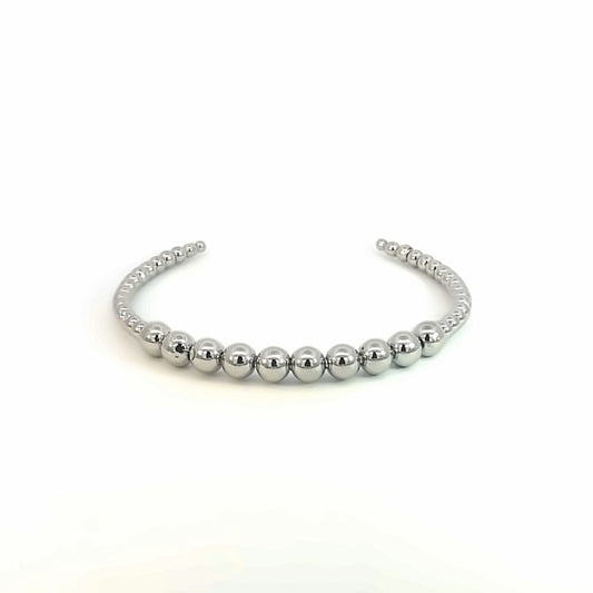A polished silver cuff bracelet features a graduated design of reflective metallic beads against a clean white background.