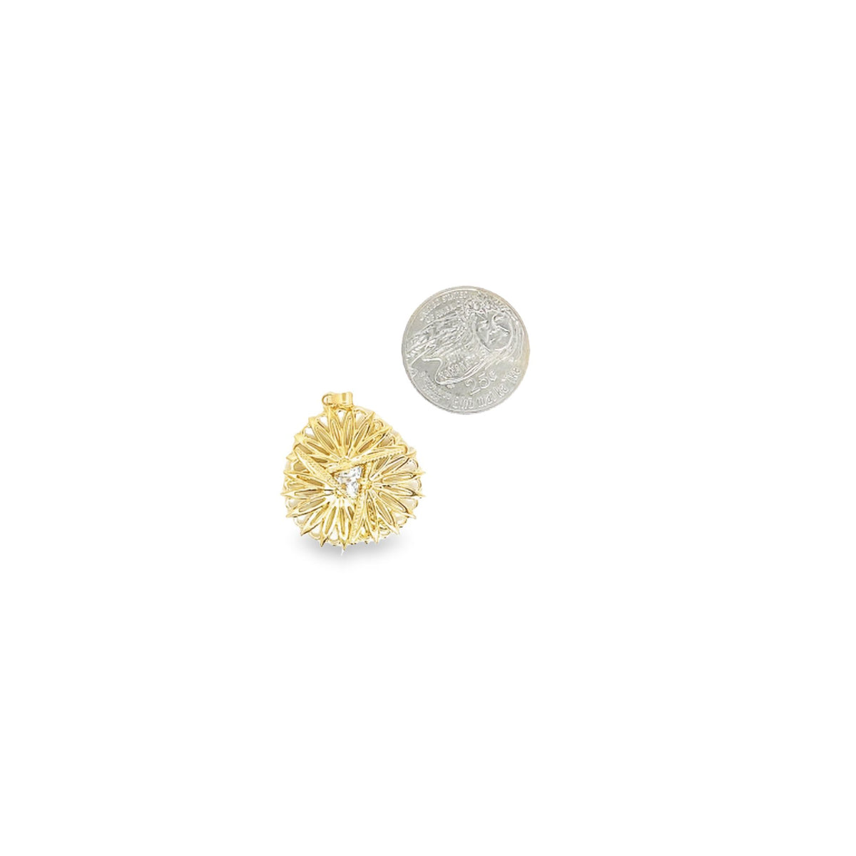A detailed gold pendant with a central cubic zirconia stone rests beside a quarter coin for size comparison on a white background.